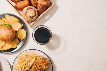 fast food and unhealthy eating concept - close up of fast food snacks and cola drink on white table