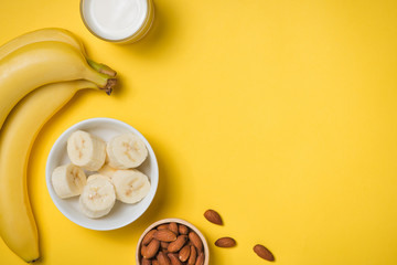 Almond milk in a glass with almond nuts and bananas on a yellow background. Healthy food and drink...