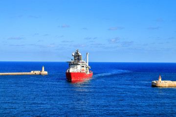Ship approaching Valletta bay in Malta between two lighthouses.