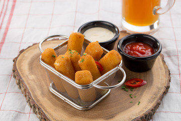 Delicious mozzarella cheese sticks breaded with ketchup and mayo in the background