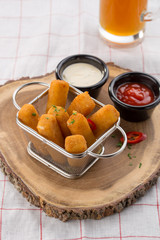Delicious mozzarella cheese sticks breaded with ketchup and mayo in the background