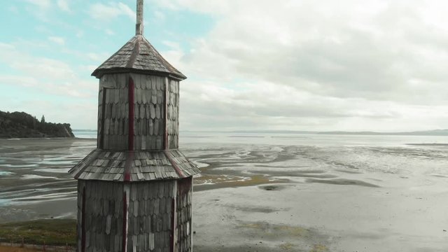 Aerial view of the tower in the wooden church facing the ocean, island of Chiloe. 4k