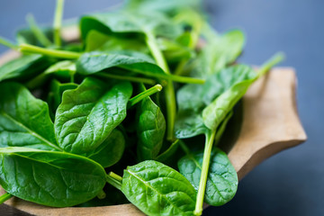 Healthy baby spinach leaves in wooden bowl closeup