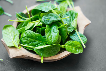 Healthy baby spinach leaves in wooden bowl closeup