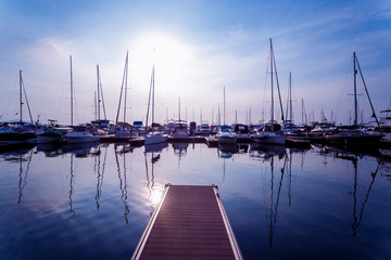 Fototapeta na wymiar Beautiful view of marina and harbor with yachts and motorboats. Sunset at the ocean.