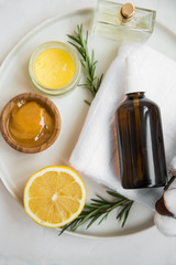 Organic skincare ingredients with towel, face mist and manuka honey, natural treatments ingredients with lemon, honey, balm salve, rosemary herb, spa still life setting