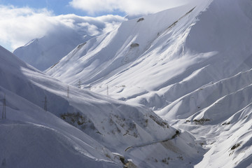 The road to the mountain gorge in winter. Snow-covered slopes of the Caucasus Mountains.