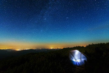 The starry sky in the mountains witha galaxy is a Milky way on the background of a tourist tent.