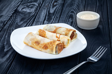 Homemade pancakes with stuffing on a dark wooden background. Ukrainian cuisine. Restaurant, food menu, recipe, cafe concept. Free copy space for text. Close up crepe