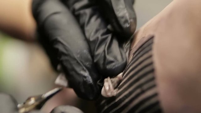 Beautiful female tattoo master makes tattoo on skin of the client, closeup macro