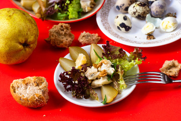 Mixed salad, pear, quail egg, bread on red.