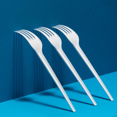 White forks with shadows on a mixed blue background