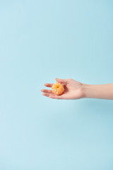 cropped view of woman holding peeled tangerine in hand isolated on blue
