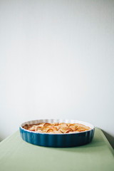 Baked apple pie in ceramic bowl on table with green tablecloth