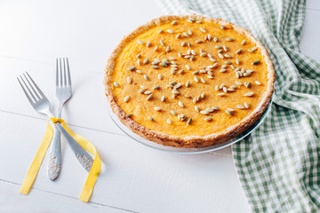 Pumpkin pie on plate served on white table with red checkered napkin 