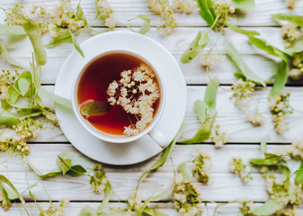 Cup of linden tea on linden blossom background. Herbal medicine.
