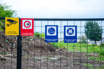 Fenced construction site with warning signs about work in progress.