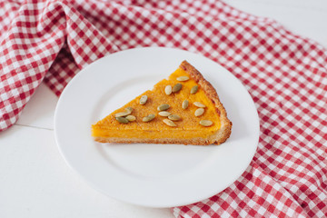 Pumkin pie with seeds on white plate with spoon and napkin
