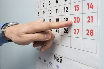 The office specialist's hand points to the day off on the wall calendar