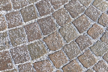 Kopfsteinpflaster mit Schneekörnern