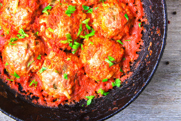 Meatballs in tomato sauce garlic and parsley in an iron frying pan on a white wooden background. Top view. Copy space