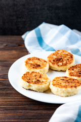 Cottage cheese pancakes on dark wooden background.