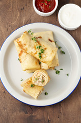 Savory crepe rolls with ground meat filling served with sour cream and tomato sauce