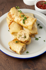 Savory crepe rolls with ground meat filling served with sour cream and tomato sauce