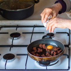left side view of a hand which is cooking omelette with Turkish sausage. purposely blurred.