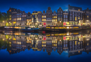 Cityscape of Amsterdam at night with reflection of buildings on water