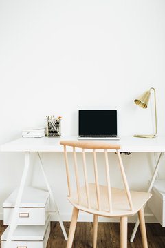 Home office desk workspace with laptop, golden lamp, stationery on white desktop. Modern interior design concept.