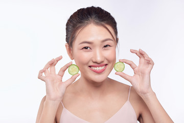 Obraz na płótnie Canvas Young asian woman with cucumber slice in her hands isolated on white background
