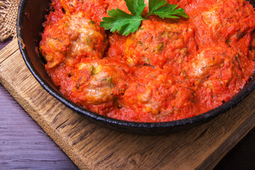 Meatballs in tomato sauce garlic and parsley in an iron frying pan on a dark brown wooden background. Top view. Copy space