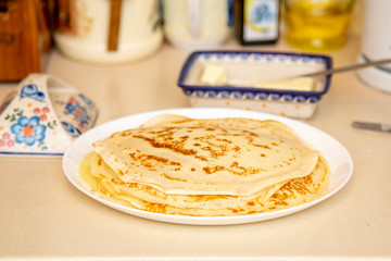 pancakes on a white plate are on the table next to a butter dish