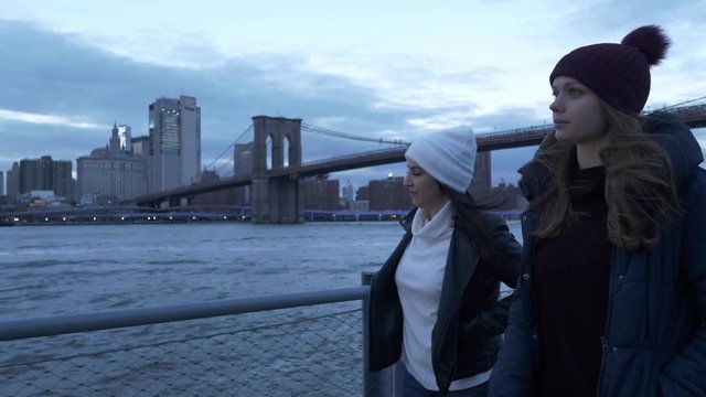 Two friends walk along the amazing skyline of Manhattan in the evening
