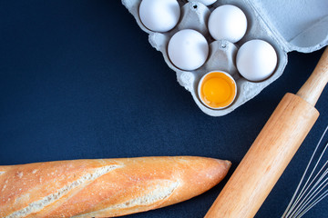 bread on the table with eggs, rolling pin and whisk