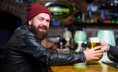 Brutal hipster bearded man sit at bar counter. Friday evening. Bar is relaxing place to have drink and relax. Hipster relaxing at bar. Man with beard spend leisure in dark bar. Brutal lonely hipster