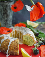 Lemon pound cake with poppy seeds. Red poppy flowers and flying petals and butterfly