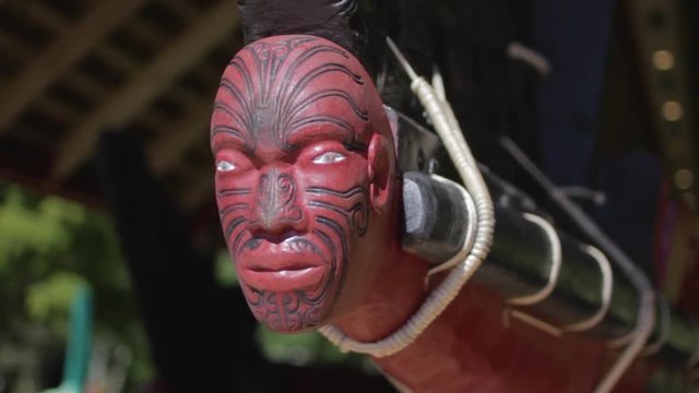 Closeup of the a maori sculpted head in the front of a traditional wooden boat in new zealand.