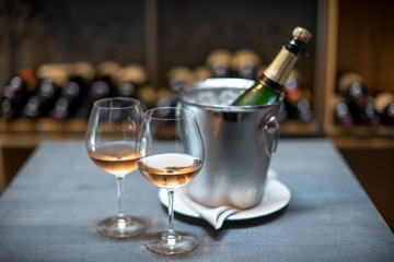 A bottle of champagne in a bucket with ice on the table. Two cold glasses of sparkling wine.
