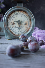 fresh plums were scattered on the table and vintage scales