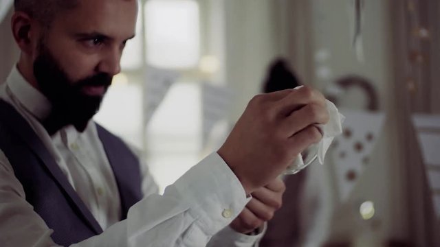 Two men with bows and vests setting a table for an indoor party.