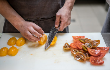 Cutting tomatoes with a kitchen knife. Chef. A restaurant.