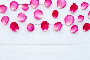 Rose petals on white wooden background.
