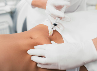 Injection into female belly, body mesotherapy. Beautician removing cellulite on the abdomen using beauty injections. - obrazy, fototapety, plakaty
