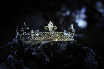 mysterious and magical photo of gold king crown over the stone covered with moss in the England...