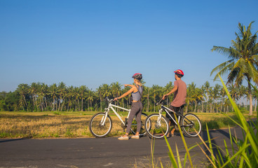 Couple riding a bicycle through the tropical island of Bali