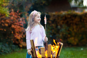 Child with smores at fire. Kids roast marshmallow.