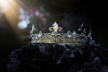 mysterious and magical photo of gold king crown over the stone covered with moss in the England...