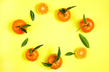 Close up image of juicy organic whole & halved tangerines with green leaves, visible core texture, isolated yellow background, copy space. Macro shot of bright citrus fruit slices. Top view, flat lay.